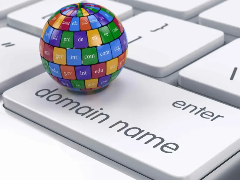 Colorful globe of domain extensions such as com, org and edu resting on a keyboard key labeled domain name
