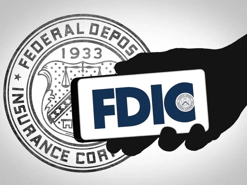 Hand silhouette holding a smartphone that shows the FDIC logo in front of the Federal Deposit Insurance Corporation seal