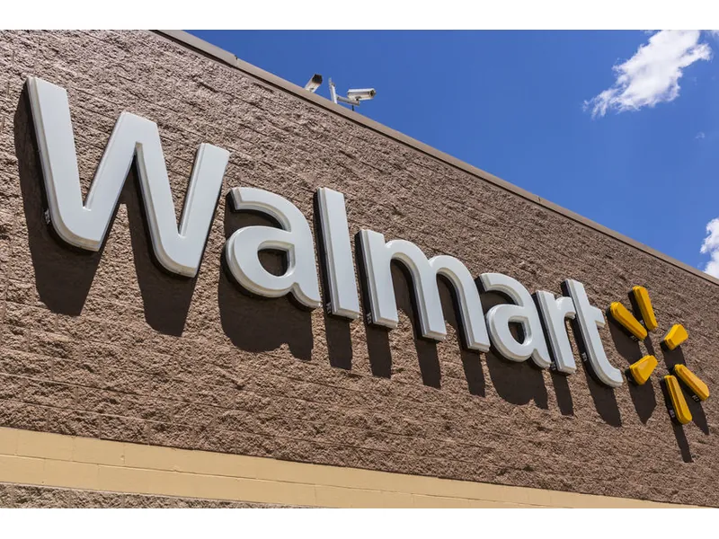 Walmart store sign with the yellow spark logo on a tan brick wall under a blue sky