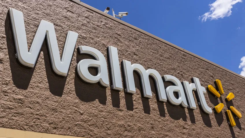 Walmart store sign with the yellow spark logo on a tan brick wall under a blue sky